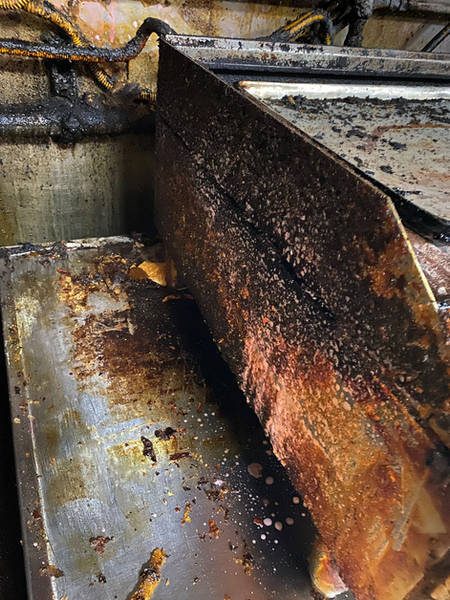 Griddle side panel with heavy burnt-on grease before cleaning